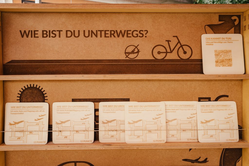 Ein mobiles Holregal mit herausnehmbaren Holztafeln. Die Überschrift lautet "Wie bist du unterwegs?".