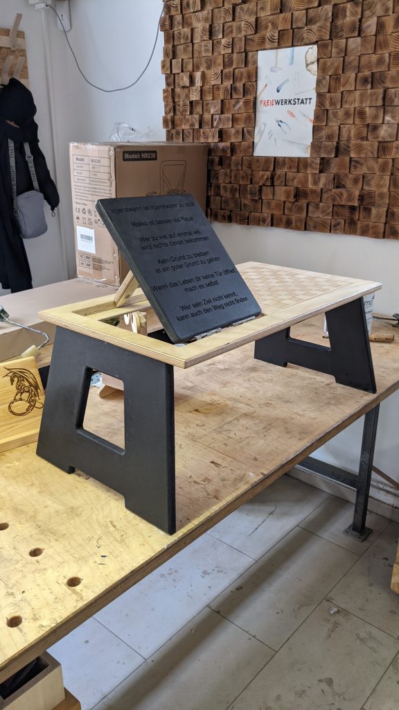 Ein Tablett aus Holz zum Aufstellen z.B. im Bett oder auf dem Sofa. Links ist eine Spüchetafel zu sehen, rechts ein Schachbrett.